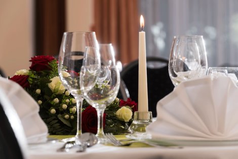 Weingläser, Blumen und eine Kerze auf dem Tisch
