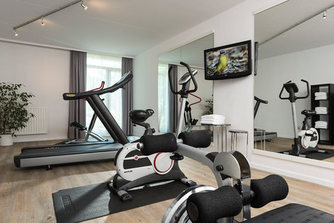 Gym with a treadmill and exercise bicycle in Wyndham Garden Kassel hotel